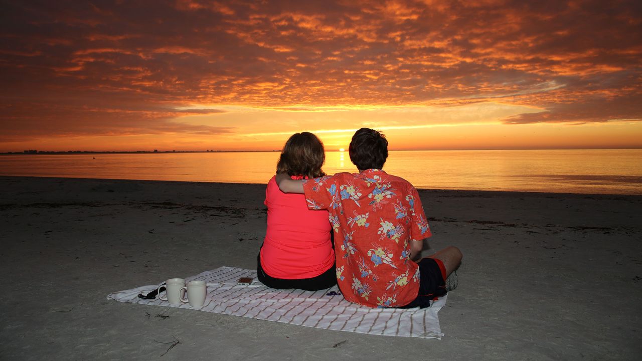 Diane Williams and her son, Elliot, watch the sun rise on Lighthouse Beach at Sanibel.
