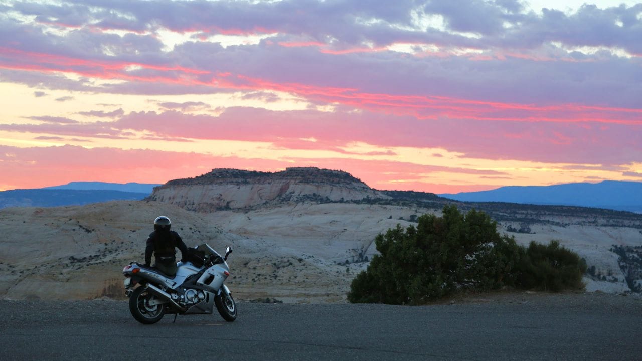 Un motocycliste s'arrête pour admirer le coucher du soleil depuis l'étroite crête de « The Hogback ».