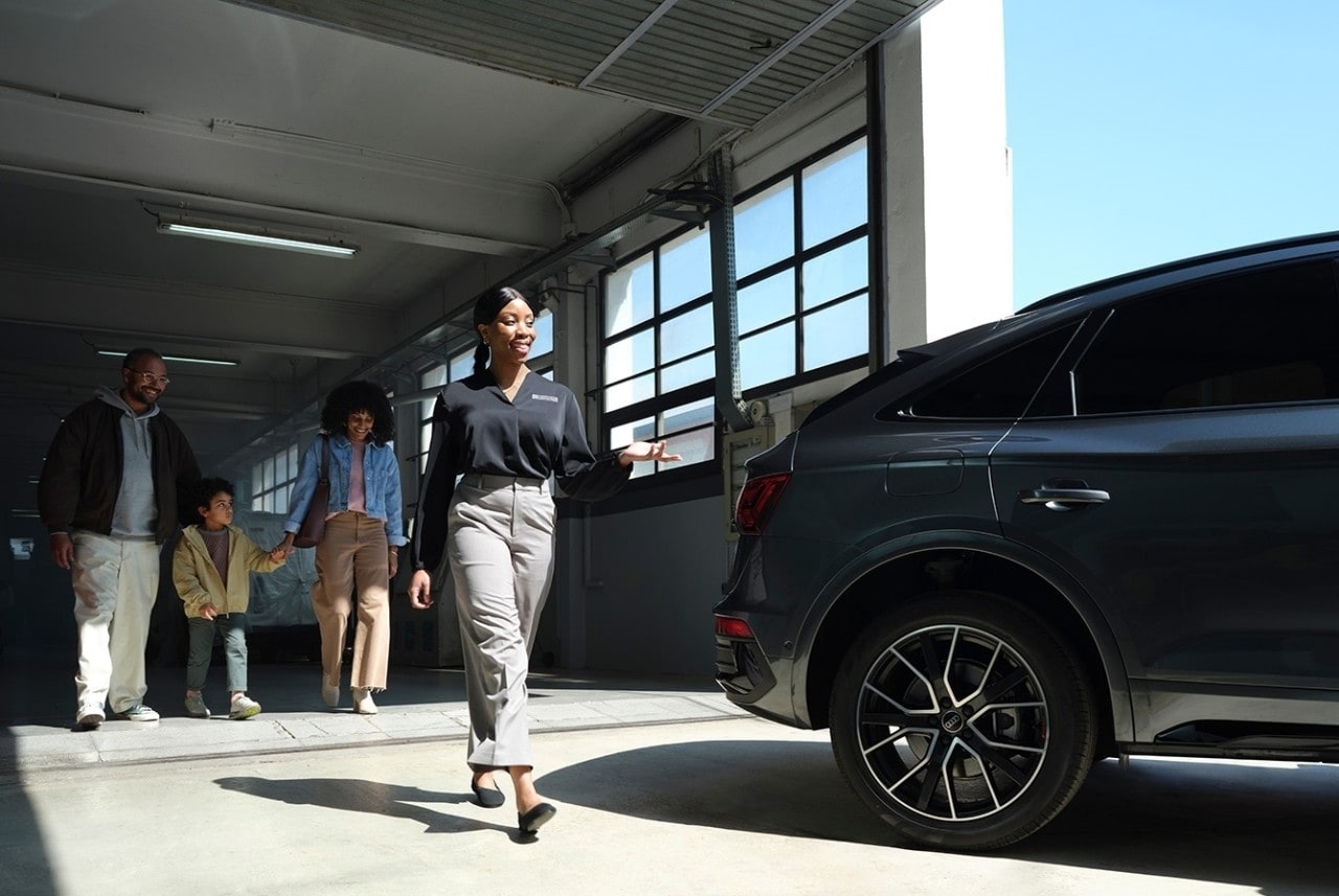 Woman handing man his rental car keys in front of the car in the rain.